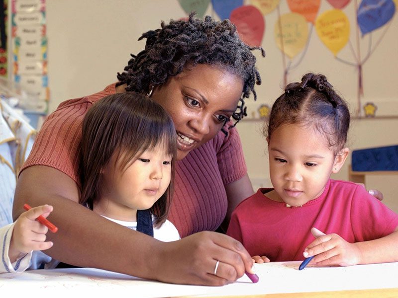 A woman and two children drawing on paper.